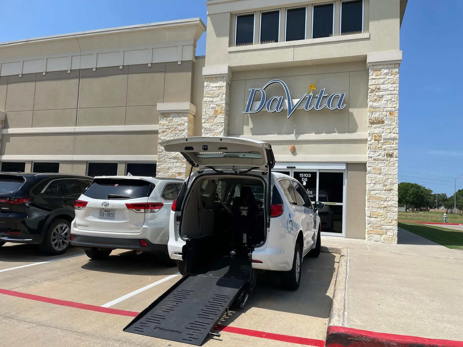 A Texas Mobile MD wheelchair-accessible van with its ramp down outside a DaVita dialysis center